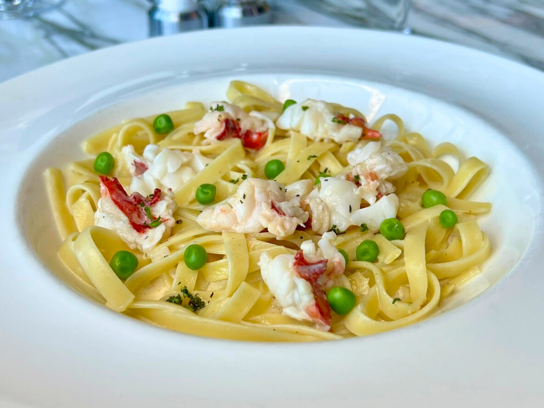 A plate of fettuccine tossed with peas and creamy crab or seafood, garnished with herbs.