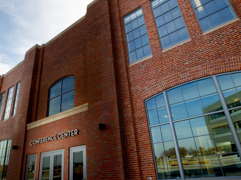 A red-brick building with big windows and a sign reading &ldquo;CONFERENCE CENTER&rdquo; above the entrance doors.